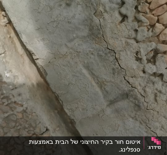 סדקים בקיר בטון עם אבנים קטנות